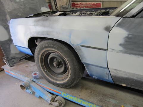 1991 Ford LTD Crown Victoria - A car is being worked on in a repair shop, showing primer and bodywork on the fender and door.