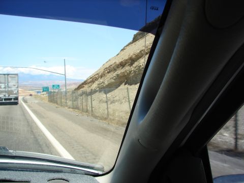 1992 Ford Taurus - View from inside a vehicle driving on a highway with a large truck ahead and a rocky hillside to the side.