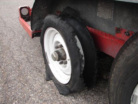 1992 Ford Taurus - A trailer's flat tire is severely damaged, with the rubber torn and exposed on the rim.