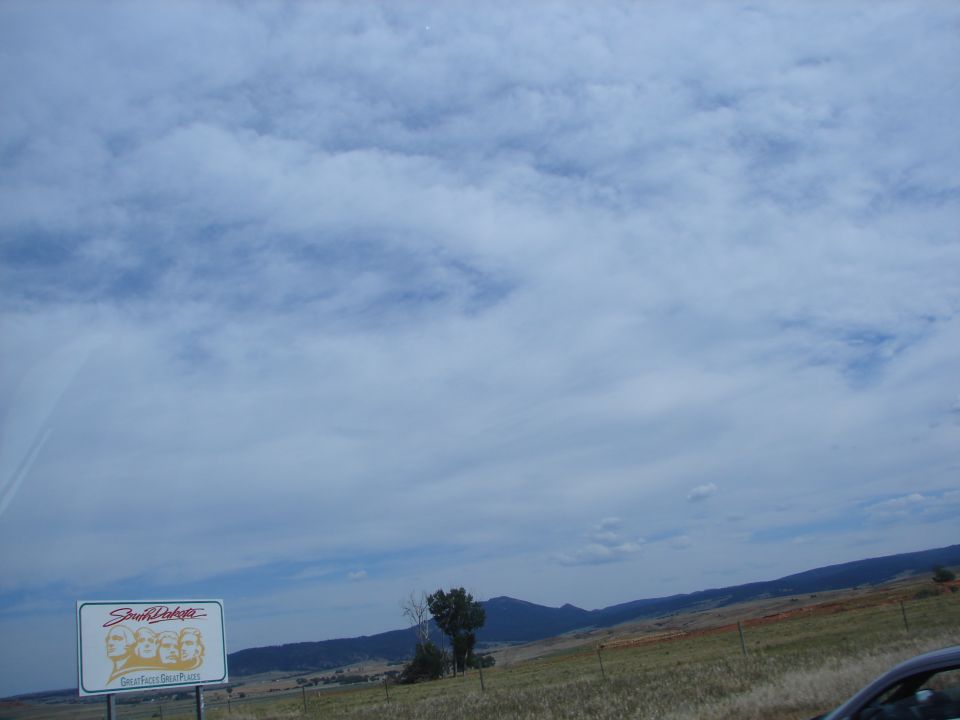 South Dakota sign showing Mount Rushmore faces and text, with a landscape background