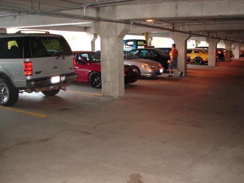 1992 Ford Taurus - Several cars are parked in a concrete parking garage, including an SUV, a red sedan, and a silver sedan.