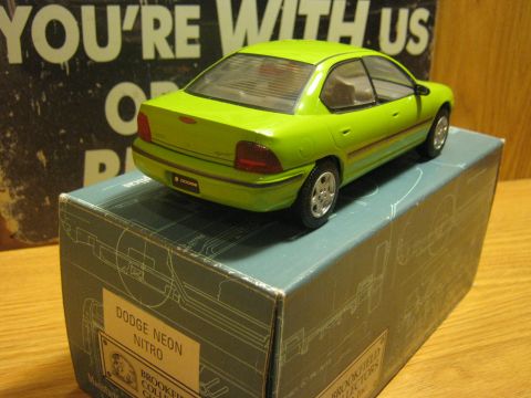 2010 Mitsubishi Outlander - A green Dodge Neon model car is displayed on top of its packaging, which features technical diagrams.