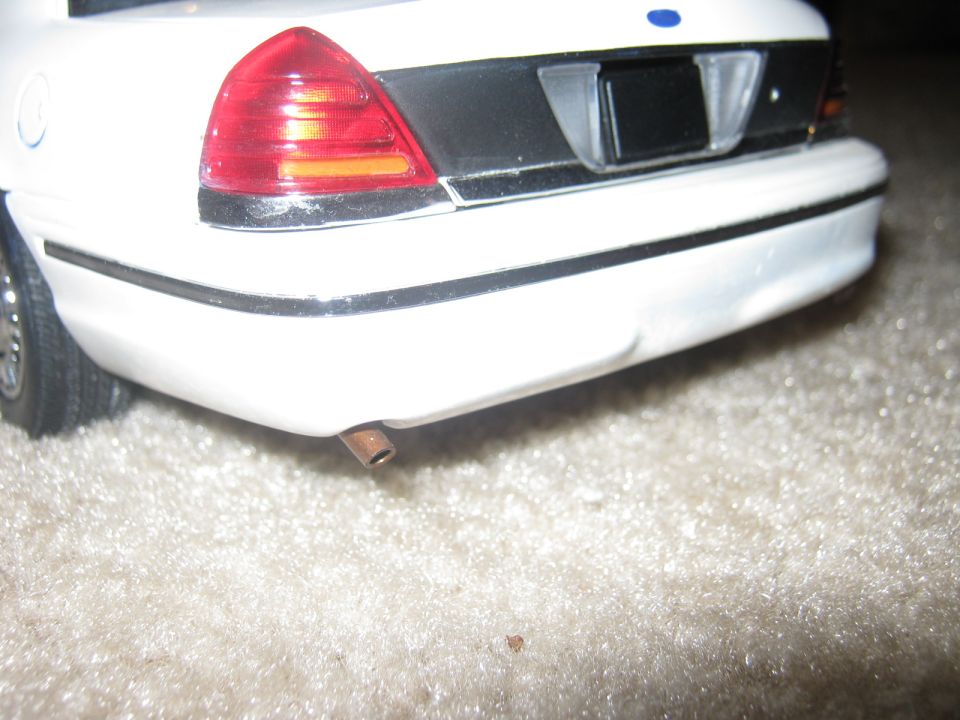 rear bumper and taillight of a white toy police car with a visible exhaust pipe