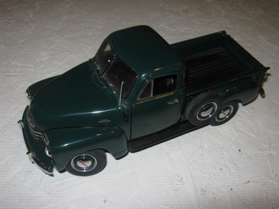 Dark green pickup truck model with chrome accents, spare tire on the side, viewed from a 3/4 front angle