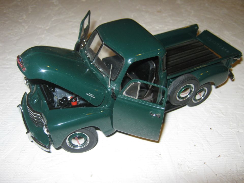Green pickup truck model with hood and doors open, showing engine detail