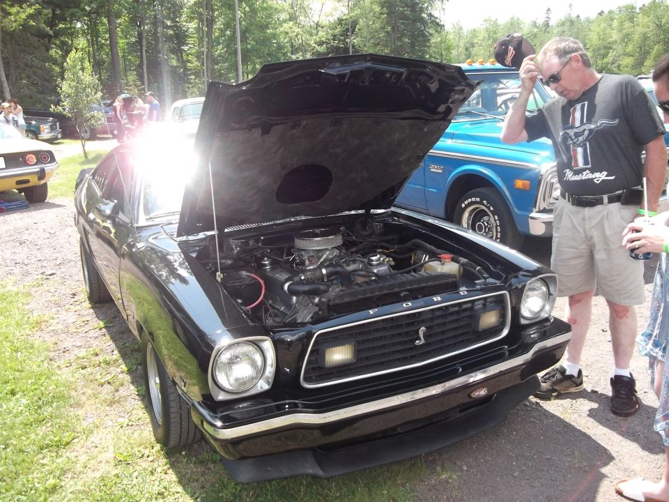 Black 1978 Ford Mustang II with hood open, showing engine. Front view