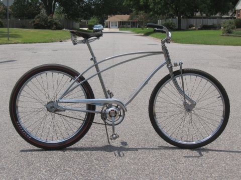1994 Ford Bronco - A classic silver cruiser bicycle with a distinctive frame and red-striped tires is parked on an asphalt road.