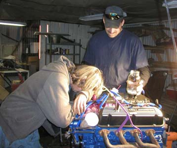 1988 Ford Bronco - Mechanics work on an engine in a dimly lit garage.