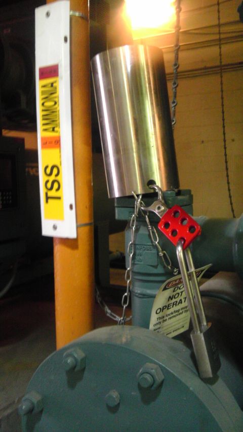 1989 Ford Bronco - A safety lock is attached to a valve on industrial piping, with an ammonia warning sign nearby.