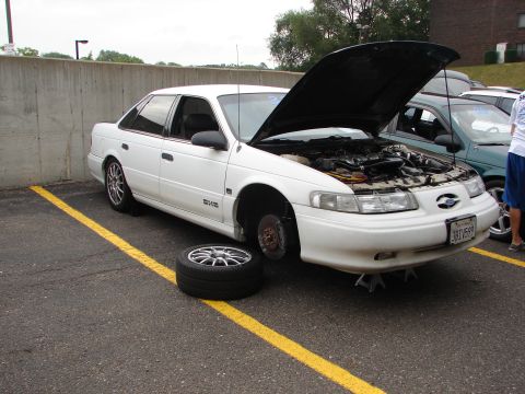 1992 Ford Taurus - White 1992 Ford Taurus undergoing maintenance in a parking lot.
