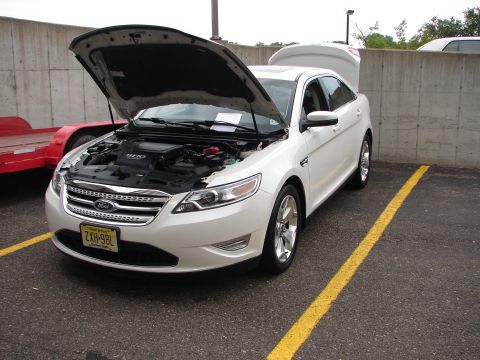 1992 Ford Taurus - White Ford Taurus SHO with hood and trunk open, parked in a lot.