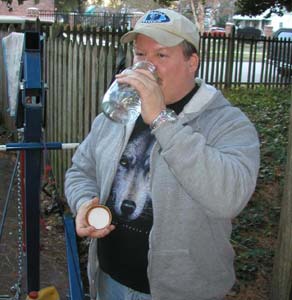 1988 Ford Bronco - A man in a gray hoodie, wolf-print T-shirt and ball cap drinks from a clear glass jar in a fenced backyard, holding the lid in his other ha…