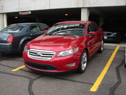 1992 Ford Taurus - A red Ford sedan is parked in a garage, with other vehicles visible in the background.
