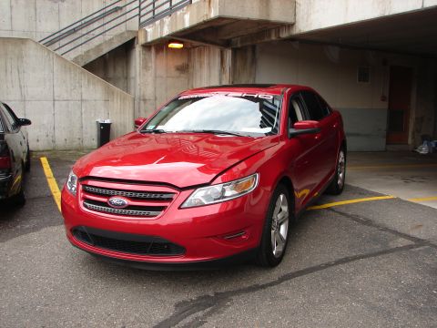 1992 Ford Taurus - A red sedan is parked in a lot, with a black car visible to its left.