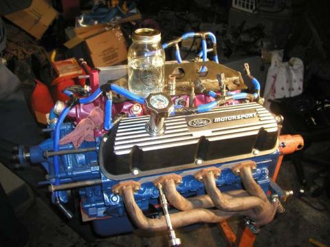 1988 Ford Bronco - A blue Ford V8 short block on an engine stand with finned aluminum Ford Motorsport valve covers, blue plug wires, chrome oil filler and rus…