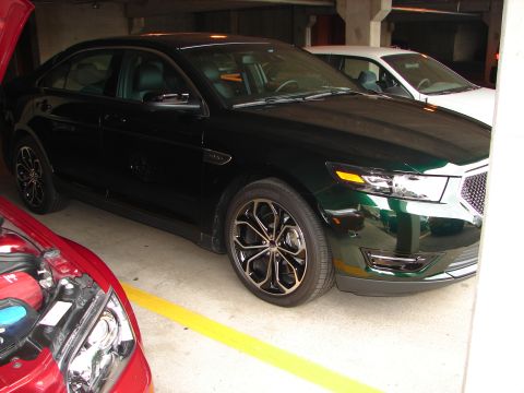 1992 Ford Taurus - A dark green Ford Taurus is parked in a garage, partially obscured by other vehicles.