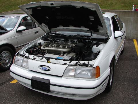 1992 Ford Taurus - A white 1992 Ford Taurus SHO is parked with its hood open, revealing the engine bay.