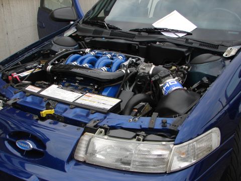1992 Ford Taurus - The engine bay of a blue 1992 Ford Taurus shows custom modifications and a Yamaha emblem.