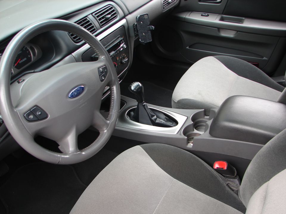 Interior view of a car showing the steering wheel, dashboard, center console, and seats. Watermark reads SUPERMOTORS.NET