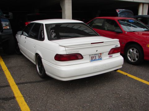 1992 Ford Taurus - Rear view of a white 1992 Ford Taurus sedan parked next to a red car.