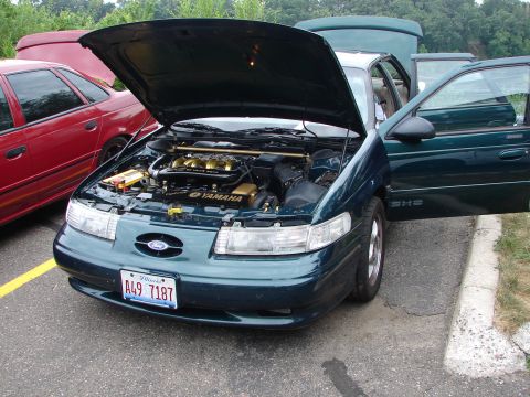 1992 Ford Taurus - The engine bay of a 1992 Ford Taurus is displayed with the hood open, alongside another vehicle.