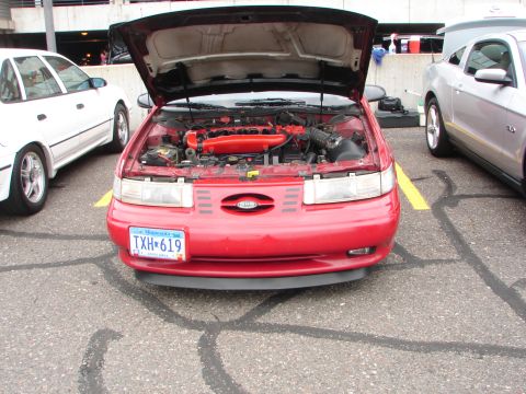 1992 Ford Taurus - A red 1992 Ford Taurus is parked with its hood open, revealing the engine compartment.