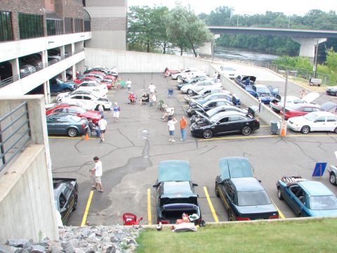 1992 Ford Taurus - A gathering of vehicles in a parking lot, with several cars displaying open hoods.