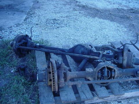 1992 Ford Bronco - Two vehicle axles are shown, one with the differential cover removed, resting on wooden pallets.