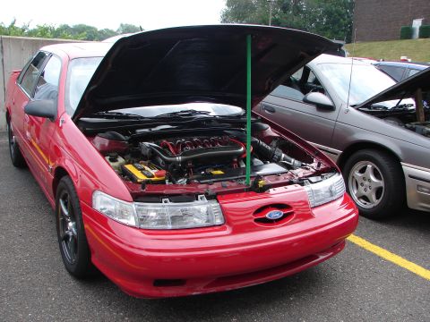 1992 Ford Taurus - A red 1992 Ford Taurus is parked with its hood open, revealing the engine, next to another Taurus.