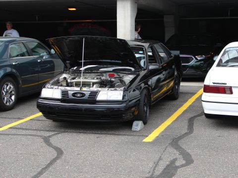 1992 Ford Taurus - Black 1992 Ford Taurus is shown with its hood open at an event.