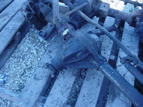 1992 Ford Bronco - Several vehicle axle parts are visible, resting on wooden planks outdoors.
