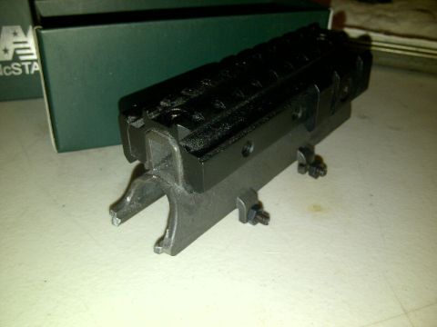 1989 Ford Bronco - A black metal part with multiple rails and visible mounting hardware is shown on a flat surface.