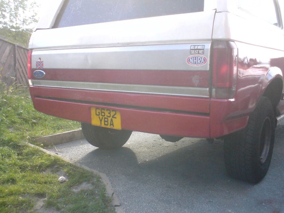 1989 Ford Bronco rear with red and silver paint, yellow license plate G632 YBA, and NHRA sticker