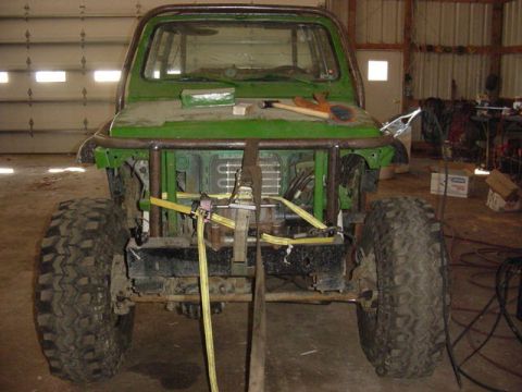 1992 Ford Bronco - This green off-road vehicle, possibly modified, is shown from the front in a garage setting, with a prominent roll cage.
