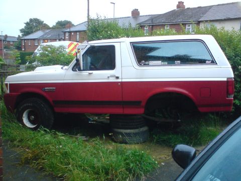 1989 Ford Bronco - This Ford Bronco is propped up on tires, with its rear wheels removed, suggesting it is undergoing maintenance or repair.