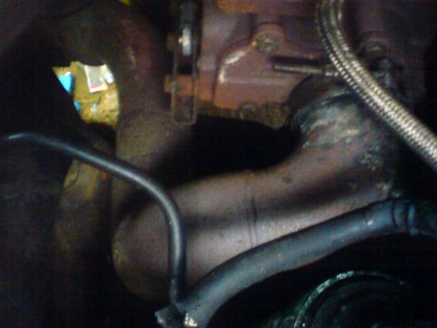 1989 Ford Bronco - Close-up view of engine components, including exhaust manifold and hoses, with visible text 'SUPERMOTORS'.