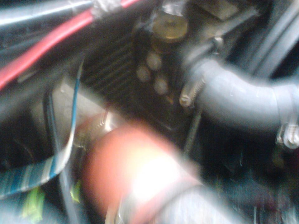 Engine bay with red hose, blue wire, and radiator fins. Watermark reads SUPERMOTORS