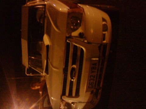 1989 Ford Bronco - Front view of a white Ford truck's grille, showing vertical bars and an oval emblem.