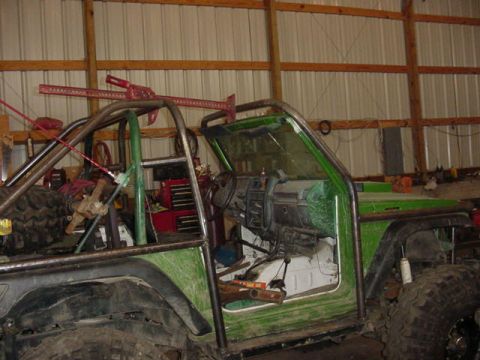 1992 Ford Bronco - This modified off-road vehicle is undergoing some work inside a garage, a prominent roll cage.