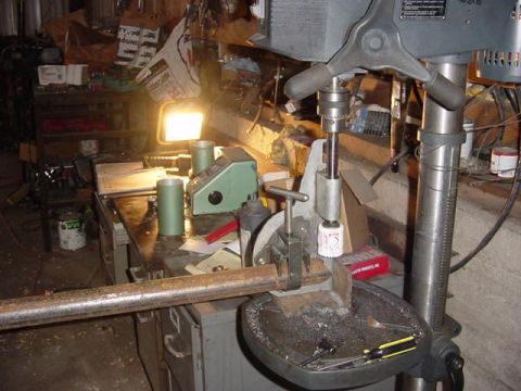 1992 Ford Bronco - A drill press is set up to cut a metal pipe in a cluttered workshop environment.