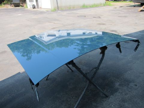 1991 Ford LTD Crown Victoria - A car hood is propped up on sawhorses outdoors, showing reflections of the surroundings in its glossy surface.