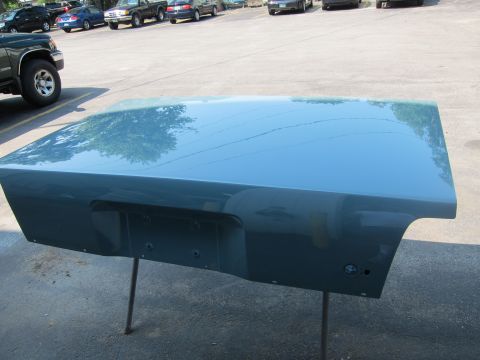 1991 Ford LTD Crown Victoria - A teal car trunk lid is mounted on a stand outdoors, reflecting the sky and trees.