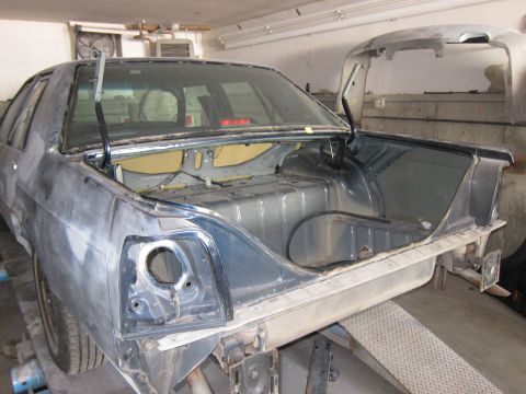 1991 Ford LTD Crown Victoria - The rear of a 1991 Ford Crown Victoria LTD is shown with its trunk open, revealing the interior structure during a repair process.