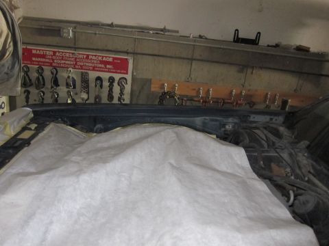 1991 Ford LTD Crown Victoria - Engine bay of a car covered with a white sheet, with a tool rack on the wall behind.