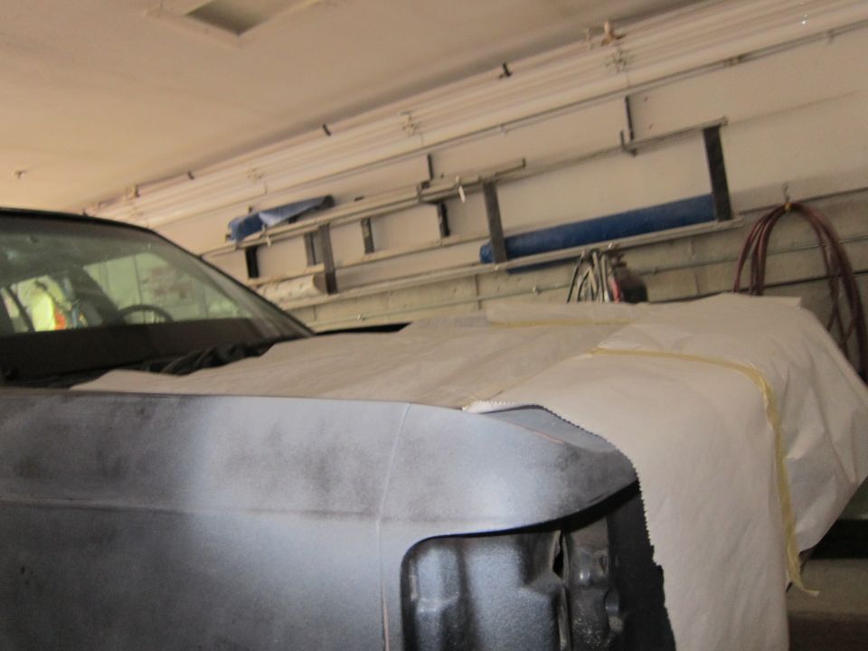 Car hood and fender covered with paper, in a garage