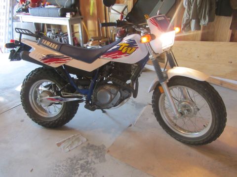1968 Ford Mustang - A white Yamaha TW 200 motorcycle is parked in a garage, showing its distinctive graphics and off-road tires.