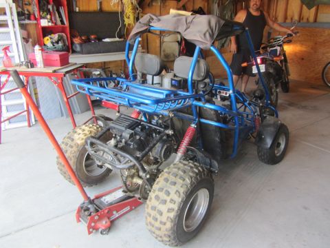 1968 Ford Mustang - A blue go-kart is parked in a garage next to a motorcycle, with a red jack supporting its rear.