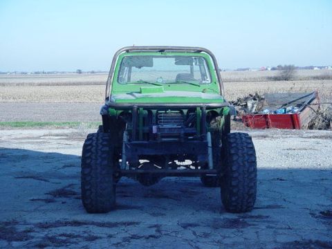 1992 Ford Bronco - A heavily modified green off-road vehicle sits in a rural setting, facing the camera.
