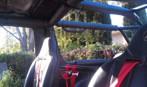 1978 Ford Bronco - The interior features a custom roll cage and racing seats, with outdoor scenery visible beyond.