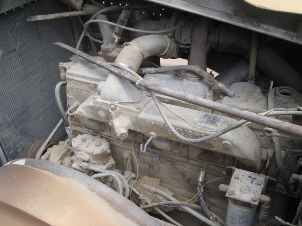 Close-up of a dusty truck engine with various hoses and pipes visible
